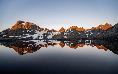 Rocky mountain peaks reflected in a small pond, mountain landscape with alpenglow at sunrise, at