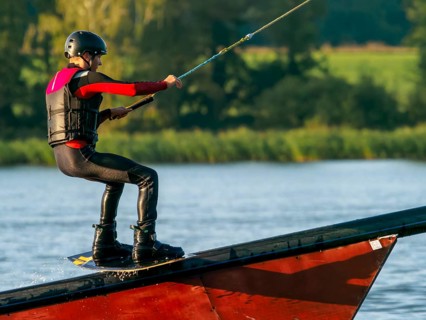 Young man with wakeboard on obstacle, water sports, water skiing in wakepark