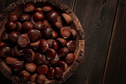 Fresh chestnuts, in a wooden bowl, top view, no people