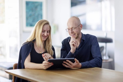 Symbolic photo. A woman and a man sit together at a table with a tablet and talk. Berlin, 13.08