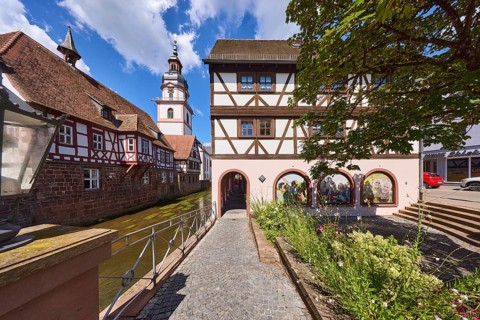 River Mümling, half-timbered houses, archway, church tower, lantern, metal railing, flower bed,