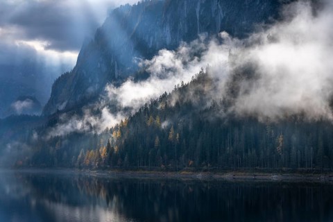 The Vordere Gosausee in autumn with a view of the Gosaukamm. Rays of sunshine shine through the