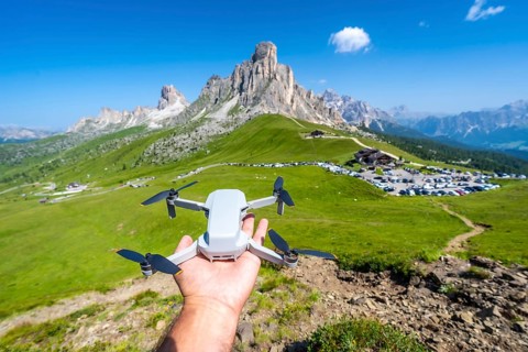 Hand holding a drone ready to fly over passo giau in the italian dolomites, showcasing the