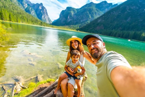 Happy family enjoying summer vacation taking a selfie at lake dobbiaco with the dolomites in the