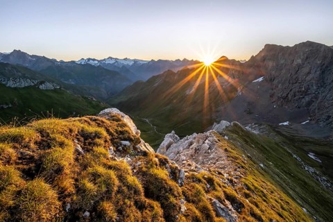 Mountain landscape at sunrise with sun star, view of mountain peaks of the Venediger group and into