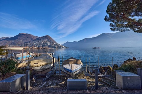 Motorboats, lake, hilly landscape with village, haze, blue sky with cirrostratus clouds, Lake