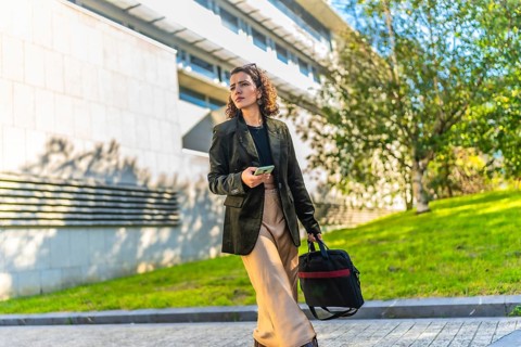 Horizontal photo with copy space of a modern arab businesswoman using mobile walking along the city