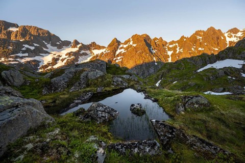 Rocky mountain peaks with reflection, small pond in moor landscape at Trollfjord Hytta, mountain