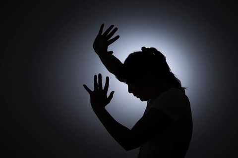 Symbolic photo on the subject of violence against woman. The silhouette of a young woman with her