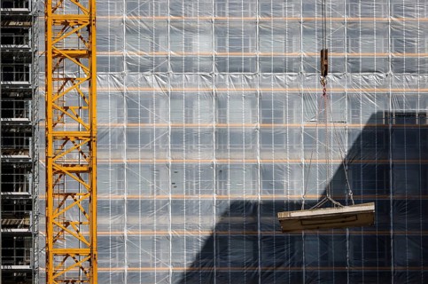 Essen, North Rhine-Westphalia, Germany - Construction crane lifts concrete section in front of