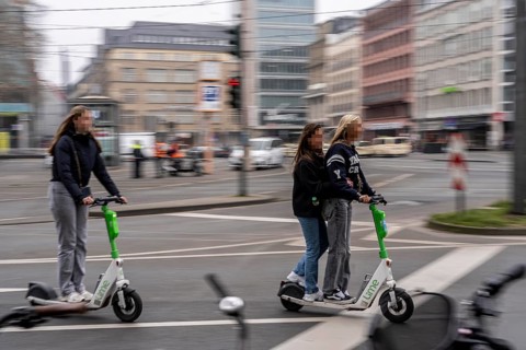 Young woman, two of them on an e-scooter, in the city centre, here at Neumarkt in Cologne, parked