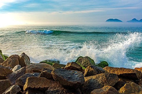 Waves crashing against the rocks of the Barra da Tijuca breakwater during dawn in Rio de Janeiro