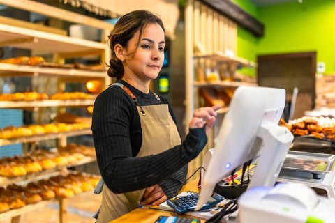 Saleswoman using the computer to calculate the bill of a customer in a bakery
