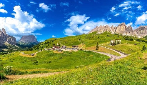 Stunning landscape of gardena pass in the italian dolomites, featuring lush meadows, winding roads,