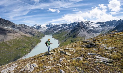 Mountaineer on the summit of Mont de la Blana, view of a blue mountain lake, Lac des Dix reservoir,