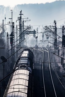 Deutsche Bahn AG tracks backlit with goods train. Overhead line, signals and infrastructure.