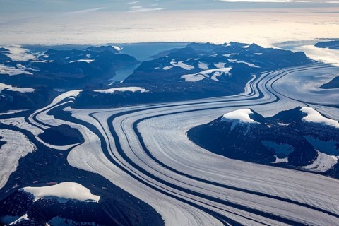 Aerial view of glaciers, glacier tongues and icy mountains on the coast, sunny, East Greenland,