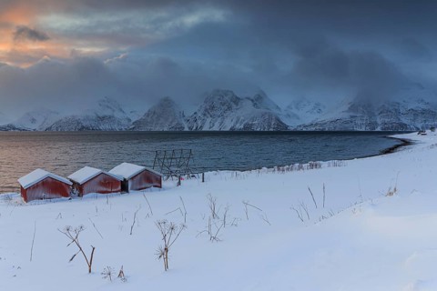 Red boat huts, coast, sea, waves, mountains, winter, snow, cloudy, windy, Lyngen Alps, Norway,