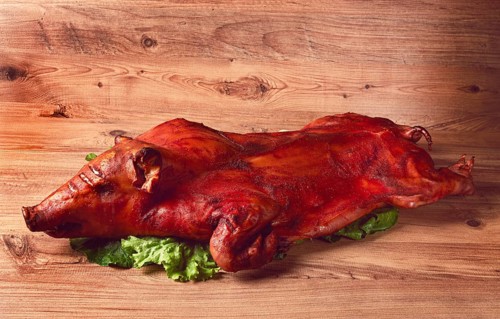 Baked, fried piglet, on a wooden table, no people, The whole piglet is baked and served on the