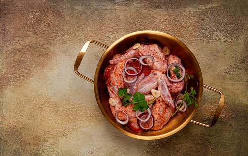 Chicken wings, in a brass saucepan, ready for cooking, grilling or baking, in a home kitchen, no