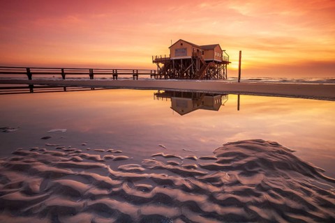 Stilt house on the beach at sunset, reflection in tidal pool, St. Peter-Ording Schleswig-Holstein