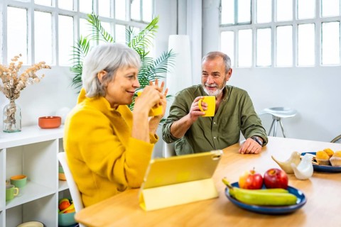 Senior couple using tablet while drinking coffee at home during breakfast in the morning