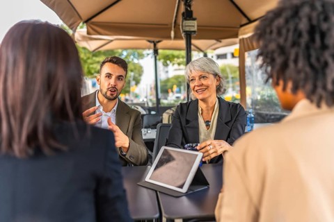 Business team talking and using digital tablet during meeting in a cafeteria