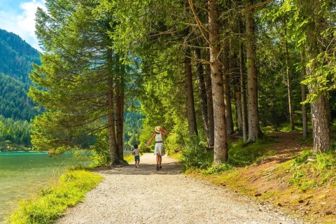 Tourists enjoying the stunning landscape of the dolomites while walking on a gravel path by the
