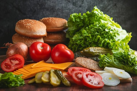 Freshly cut ingredients for a hamburger, such as lettuce, tomatoes, cheese and bun