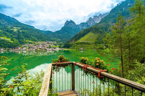 Wooden viewpoint overlooking the picturesque village of alleghe, reflecting on emerald waters