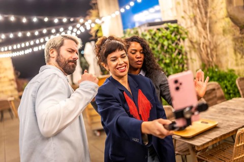 Female caucasian vlogger streaming online using the smartphone in a night party with friends