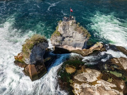 Aerial view of the Rhine Falls at low water in spring, with tourists on the viewing platform,