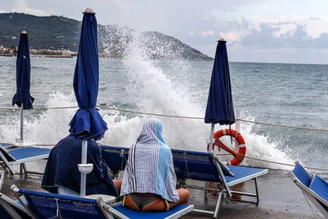 Waves crashing against the pier of a bathing jetty where a couple is sitting on deckchairs, Diana