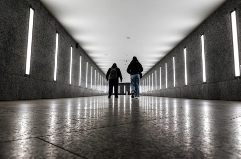 Two men walking through the tunnel subway illuminated with LED light to the underground station
