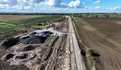 Construction vehicles are parked at an access road under construction to the High Tech Park at the