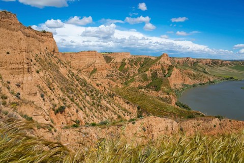Panorama einer felsigen, trockenen Landschaft mit einem Fluss und blauem Himmel mit Wolken,