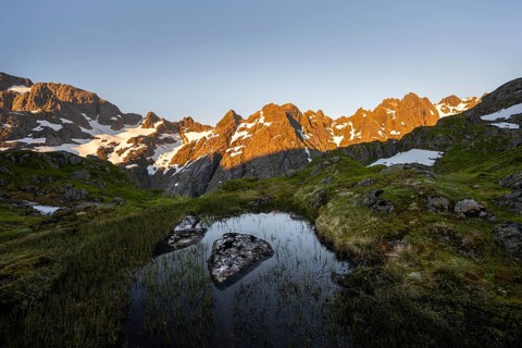 Rocky mountain peaks with reflection, small pond in moor landscape at Trollfjord Hytta, mountain