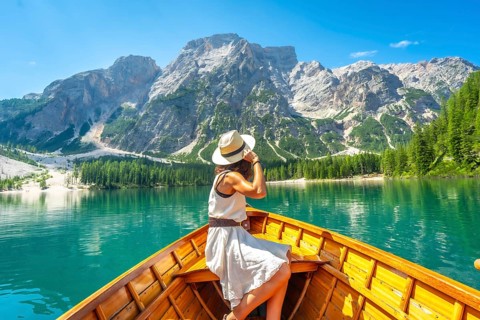 Young woman wearing a straw hat enjoying a boat trip on the turquoise waters of lake braies with