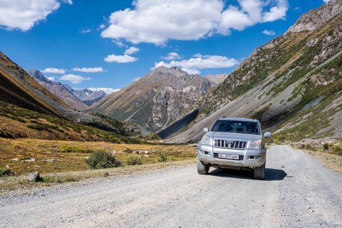Off-road vehicle on a gravel track, picturesque mountain valley, mountain landscape with white