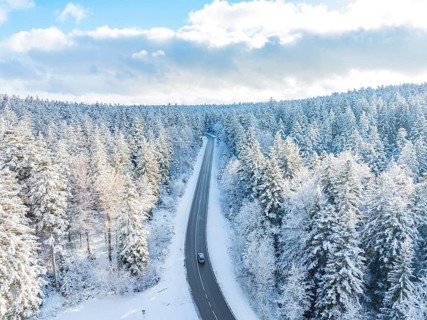 A road winds through a snowy winter forest under a blue sky, Bad Wildbad, district of Calw, Black
