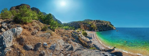Expansive Ahata Beach panorama with beach, mountain backdrop and bright sunlight over the sea,