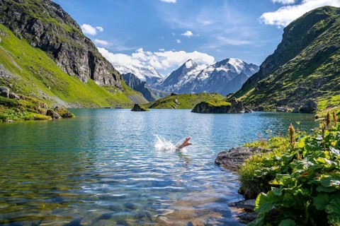 Woman taking a dip, cooling off in the mountain lake Lac de Louvie, behind the summit of the Grand