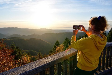 Woman photographing the sunset at Schliffkopf, near Baiersbronn, Freudenstadt district, Black