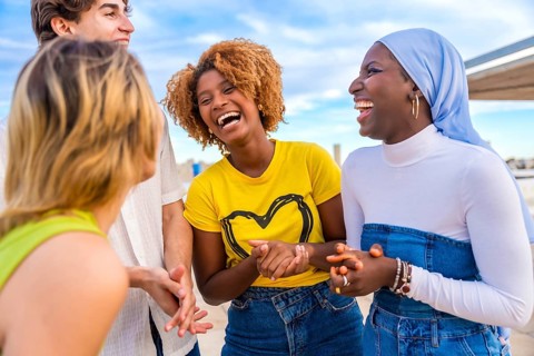 Young and smiling african woman talking to friends in a happy conversation outdoors
