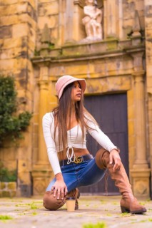 A young Latin woman with a white t-shirt, jeans and a hat enjoying the summer holidays, with a take