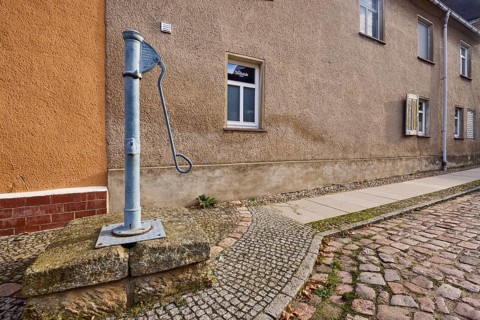 Historic pump, hand pump, pavement, cobblestones, facade with windows, Mühlberg Elbe, Elbe-Elster