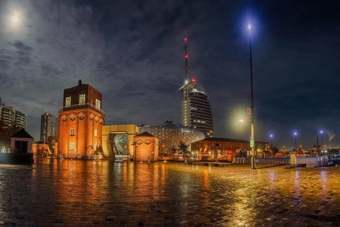 View of the old bascule bridge, the Klimahaus and a hotel in Bremerhaven at night, Bremerhaven,