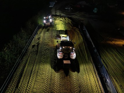 Two tractors filling and levelling a silo at night, maize harvest, Dachtel, Black Forest, Germany,