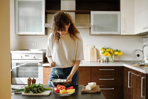 Woman makes stuffing for bell peppers in a bowl in the kitchen
