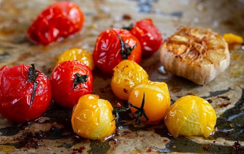 Baked cherry tomatoes, in the oven, on a baking sheet, with olive oil and spices, close-up,